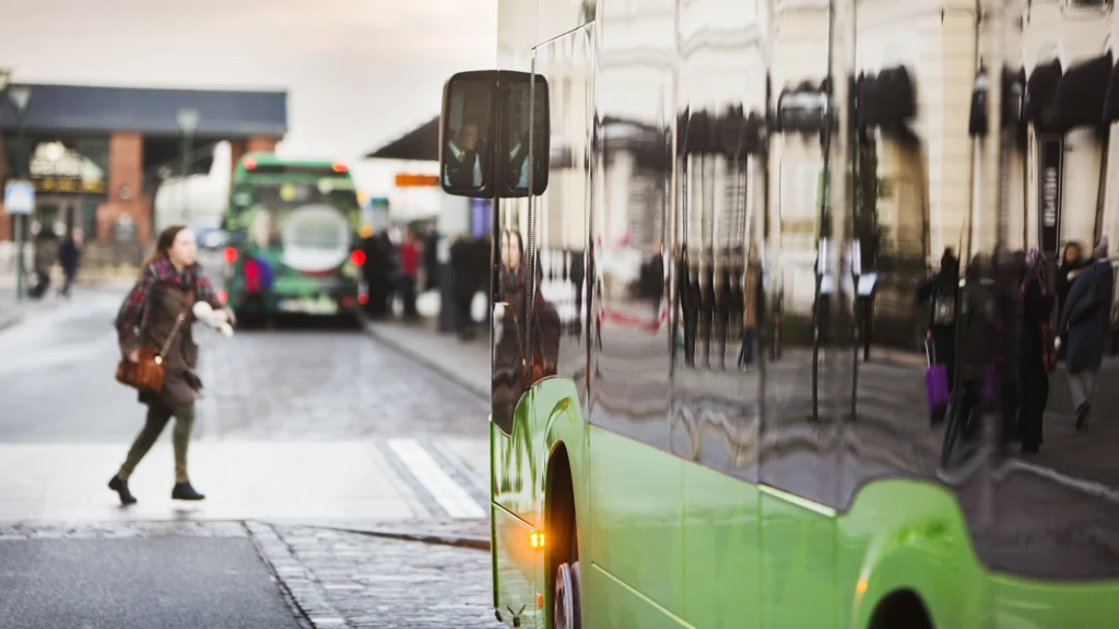 Kvinner krysser veien foran en buss