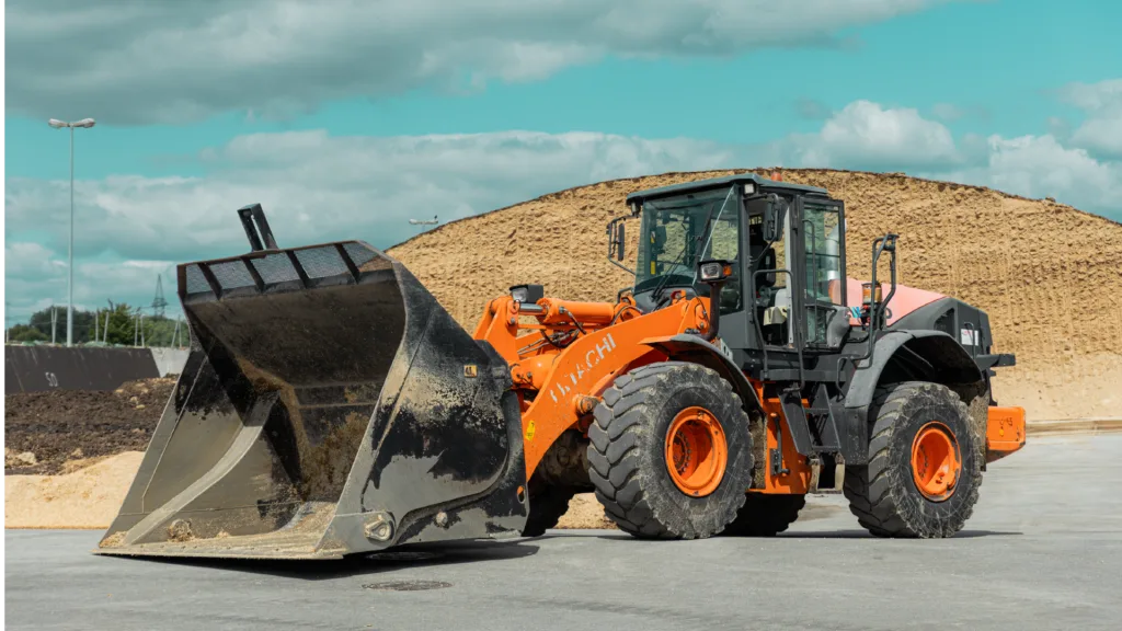 Pala gommata Hitachi arancione in un cantiere.