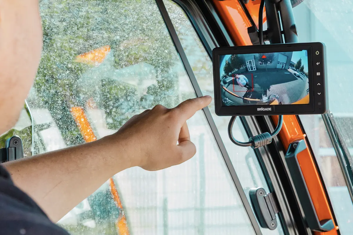 A driver pointing a monitor inside the cab showing a pedestrian being detected by the Brigade AI cameras.