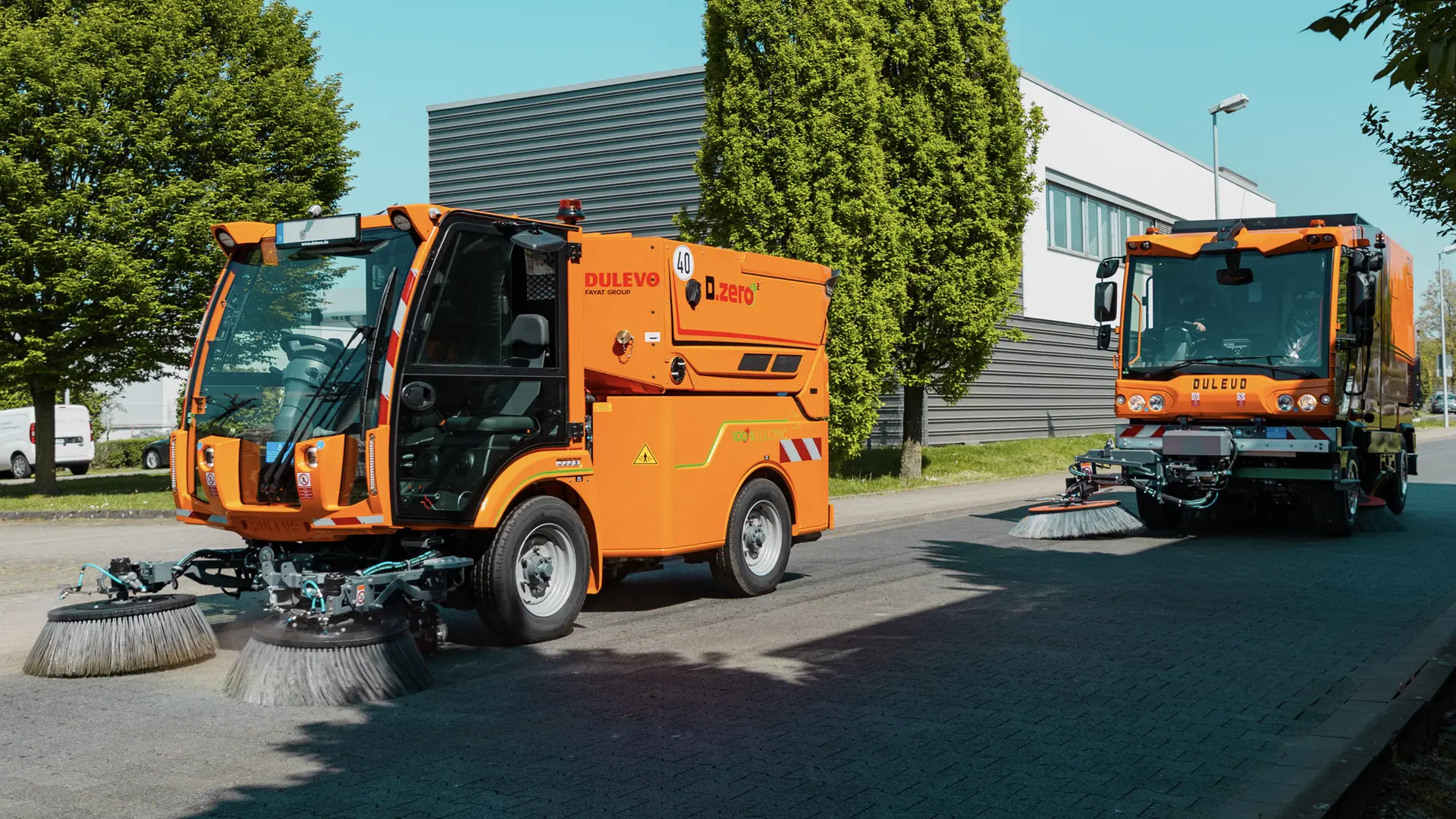 Two Deluvo road sweepers moving on a quiet road